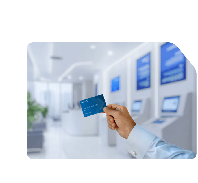 A man holding a Network payment card inside a modern banking hall with digital self-service kiosks in the background.