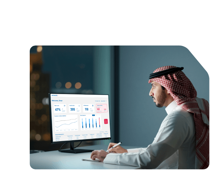Saudi man reviewing financial analytics on a Network dashboard, tracking transaction data, credit stats, and fraud alerts.
