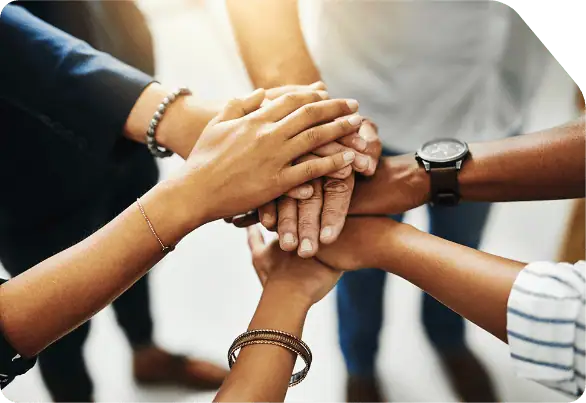 Group of people stacking hands symbolizing teamwork.