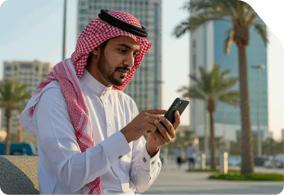 Saudi man using a smartphone in a modern city setting.